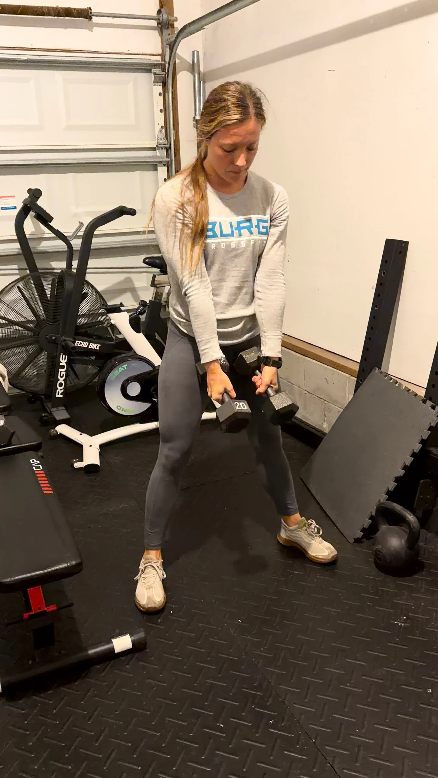 Lexi lifting dumbbells in a garage gym